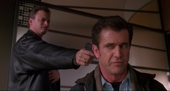 Movie still from “Ransom” (1996), directed by Ron Howard – A man getting his hair combed by another man with a gun; Close Up shot, Low angle