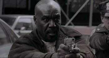 Movie still from “Ransom” (1996), directed by Ron Howard – A black and white photo of a man holding a gun; Close Up shot, Low angle