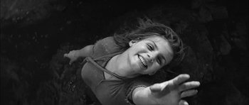 Movie still from “Rapture” (1965), directed by John Guillermin – A young girl is smiling while laying on the ground; Close Up shot, Overhead angle