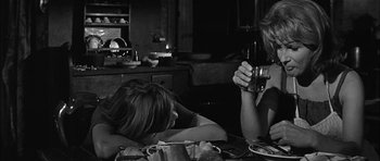 Movie still from “Rapture” (1965), directed by John Guillermin – Two women sitting at a dinner table drinking wine; Medium shot, Over the shoulder angle