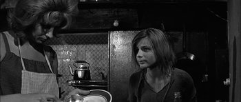 Movie still from “Rapture” (1965), directed by John Guillermin – A young woman is looking at the camera while holding a tea pot in her hand; Medium shot, Over the shoulder angle