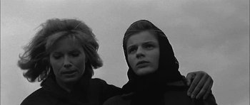 Movie still from “Rapture” (1965), directed by John Guillermin – Two women standing next to each other in front of a cloudy sky; Close Up shot, Low angle