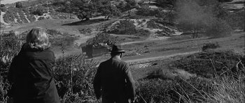 Movie still from “Rapture” (1965), directed by John Guillermin – A man standing on top of a grass covered hill; Extreme Wide shot, High angle