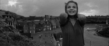 Movie still from “Rapture” (1965), directed by John Guillermin – A young girl is holding an apple in her hand; Medium shot, Low angle