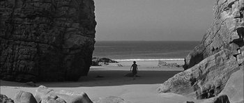 Movie still from “Rapture” (1965), directed by John Guillermin – A person standing on the beach near the water; Extreme Wide shot, High angle