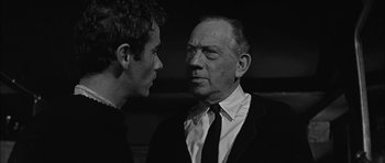 Movie still from “Rapture” (1965), directed by John Guillermin – A man in a suit talking to another man in a suit; Close Up shot, Over the shoulder angle