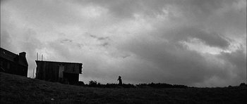 Movie still from “Rapture” (1965), directed by John Guillermin – A person standing on top of a grass covered field; Extreme Wide shot, Low angle