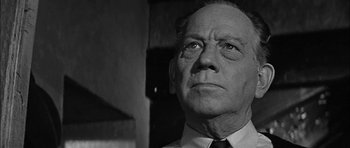 Movie still from “Rapture” (1965), directed by John Guillermin – An older man wearing a suit and tie looking off into the distance; Close Up shot, Low angle