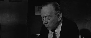 Movie still from “Rapture” (1965), directed by John Guillermin – An older man wearing a suit and tie looking at the camera; Close Up shot, Low angle