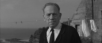 Movie still from “Rapture” (1965), directed by John Guillermin – An older man wearing a suit and tie; Close Up shot, Low angle