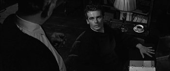 Movie still from “Rapture” (1965), directed by John Guillermin – A black and white photo of a man smoking a cigarette; Close Up shot, Over the shoulder angle