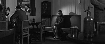 Movie still from “Rapture” (1965), directed by John Guillermin – A woman sitting on a bench in a living room; Wide shot, High angle