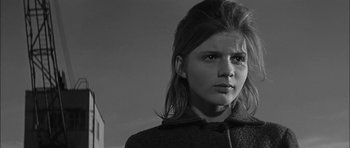 Movie still from “Rapture” (1965), directed by John Guillermin – A young woman with a long hair in a black coat; Close Up shot, Low angle