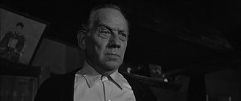 Movie still from “Rapture” (1965), directed by John Guillermin – An older man wearing a white shirt and a black jacket; Close Up shot, Low angle