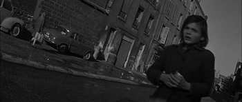 Movie still from “Rapture” (1965), directed by John Guillermin – A black and white photo of a man walking down the street; Medium shot, Low angle