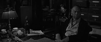 Movie still from “Rapture” (1965), directed by John Guillermin – An old man sitting at a desk in a dark room; Close Up shot, High angle