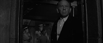 Movie still from “Rapture” (1965), directed by John Guillermin – A man standing in front of another man; Medium shot, Low angle