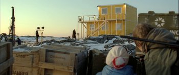 Movie still from “Rare Exports” (2010), directed by Jalmari Helander – A man walking a dog in the snow next to a building; Extreme Wide shot, Over the shoulder angle