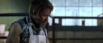 Movie still from “Rare Exports” (2010), directed by Jalmari Helander – A man with a beard and a white apron is looking down; Medium shot, Over the shoulder angle