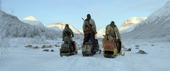 Movie still from “Rare Exports” (2010), directed by Jalmari Helander – A group of men riding on the back of a sled; Wide shot, Low angle