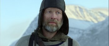 Movie still from “Rare Exports” (2010), directed by Jalmari Helander – A man with a gray beard wearing a black hat; Close Up shot, Low angle