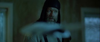 Movie still from “Rare Exports” (2010), directed by Jalmari Helander – A man with a beard wearing a black hat; Close Up shot, Low angle