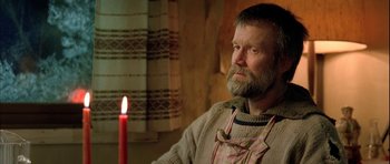 Movie still from “Rare Exports” (2010), directed by Jalmari Helander – A man sitting in front of a candle in a room; Medium shot, Low angle