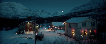 Movie still from “Rare Exports” (2010), directed by Jalmari Helander – A snow covered road at night with a lot of christmas lights; Extreme Wide shot, High angle