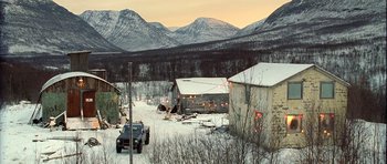 Movie still from “Rare Exports” (2010), directed by Jalmari Helander – A truck is parked in front of a building in the snow; Extreme Wide shot, High angle