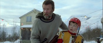 Movie still from “Rare Exports” (2010), directed by Jalmari Helander – A man and a child are standing in the snow; Medium shot, Low angle