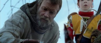 Movie still from “Rare Exports” (2010), directed by Jalmari Helander – A man with a beard and a sweater looking down at a doll; Close Up shot, Low angle