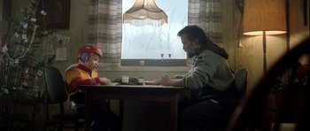 Movie still from “Rare Exports” (2010), directed by Jalmari Helander – A man sitting at a table with a little girl; Medium shot, Low angle