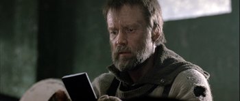 Movie still from “Rare Exports” (2010), directed by Jalmari Helander – A man looking at his cell phone while sitting in a chair; Close Up shot, Over the shoulder angle
