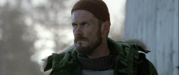 Movie still from “Rare Exports” (2010), directed by Jalmari Helander – A person with a beard wearing a hat; Close Up shot, Over the shoulder angle