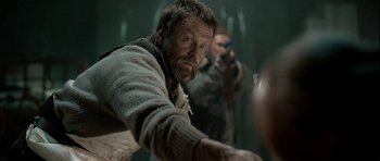 Movie still from “Rare Exports” (2010), directed by Jalmari Helander – A man with a beard is holding a gun; Medium shot, Over the shoulder angle