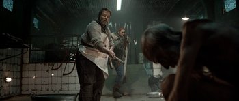 Movie still from “Rare Exports” (2010), directed by Jalmari Helander – Two men in a warehouse holding a baseball bat; Medium shot, Over the shoulder angle