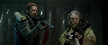 Movie still from “Rare Exports” (2010), directed by Jalmari Helander – A man holding a gun and another man holding a gun; Medium shot, Low angle