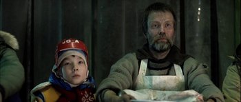 Movie still from “Rare Exports” (2010), directed by Jalmari Helander – A man and a child sitting at a table; Close Up shot, Low angle