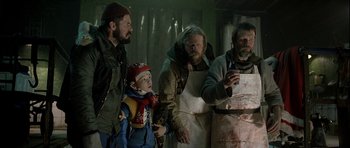Movie still from “Rare Exports” (2010), directed by Jalmari Helander – A group of men standing around a boy with a knife; Medium shot, Low angle