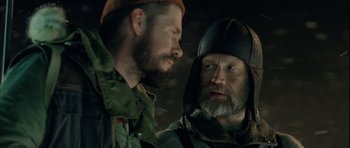 Movie still from “Rare Exports” (2010), directed by Jalmari Helander – Two bearded men wearing hats looking at each other; Close Up shot, Over the shoulder angle
