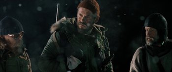 Movie still from “Rare Exports” (2010), directed by Jalmari Helander – A man in a parka and a hat is holding a gun; Close Up shot, Low angle
