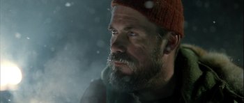 Movie still from “Rare Exports” (2010), directed by Jalmari Helander – A man with a beard wearing a red hat; Close Up shot, Over the shoulder angle