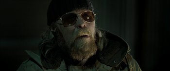 Movie still from “Rare Exports” (2010), directed by Jalmari Helander – A person wearing a hat and sunglasses; Close Up shot, Low angle