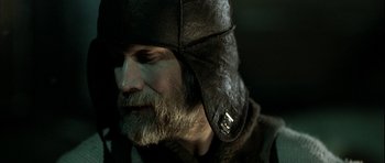 Movie still from “Rare Exports” (2010), directed by Jalmari Helander – A man with a beard wearing a leather hat; Close Up shot, Over the shoulder angle