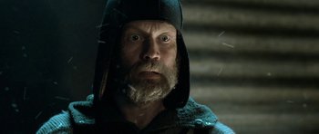 Movie still from “Rare Exports” (2010), directed by Jalmari Helander – A man with a beard wearing a black hat; Close Up shot, Low angle
