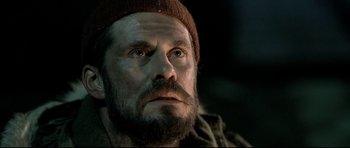 Movie still from “Rare Exports” (2010), directed by Jalmari Helander – A person with a beard wearing a hat; Close Up shot, Low angle