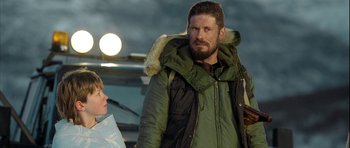 Movie still from “Rare Exports” (2010), directed by Jalmari Helander – A man in a green parka standing next to a woman in a green parka; Medium shot, Over the shoulder angle
