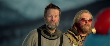 Movie still from “Rare Exports” (2010), directed by Jalmari Helander – A man with long hair and a goatee is standing next to another man with long hair; Close Up shot, Low angle
