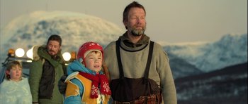 Movie still from “Rare Exports” (2010), directed by Jalmari Helander – A man and a boy standing next to each other in the snow; Medium shot, Low angle