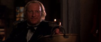 Movie still from “Ravenous” (1999), directed by Antonia Bird – A man holding a candle in front of a pot; Close Up shot, Over the shoulder angle